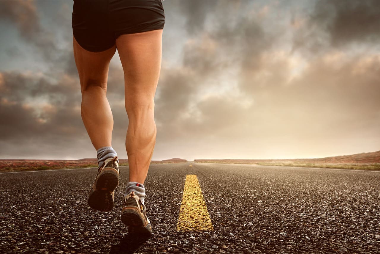 gambe di un uomo che corre lungo una strada deserta
