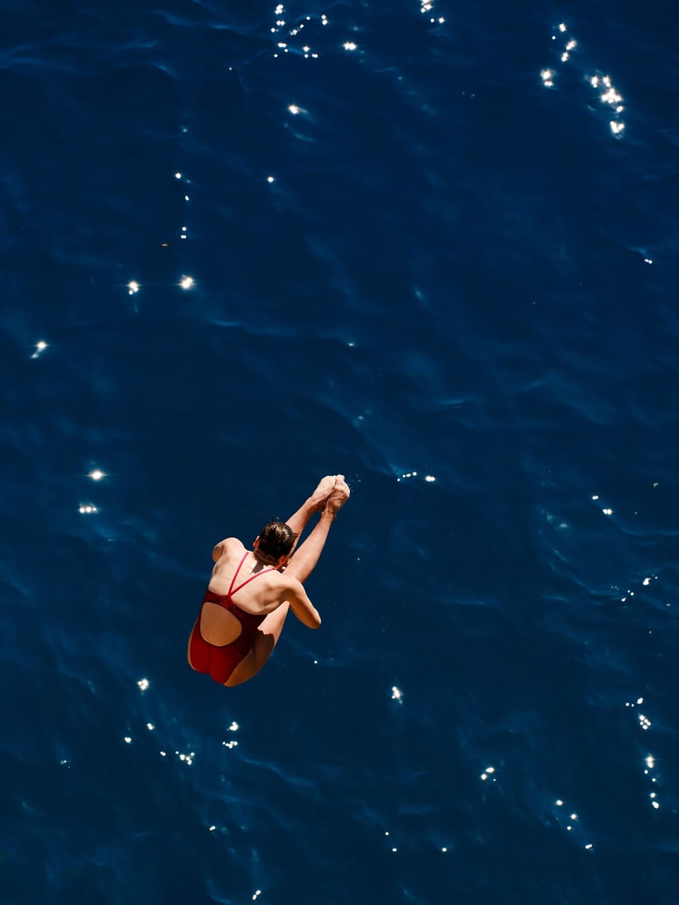 nuotatrice col costume rosso fa un tuffo nel mare