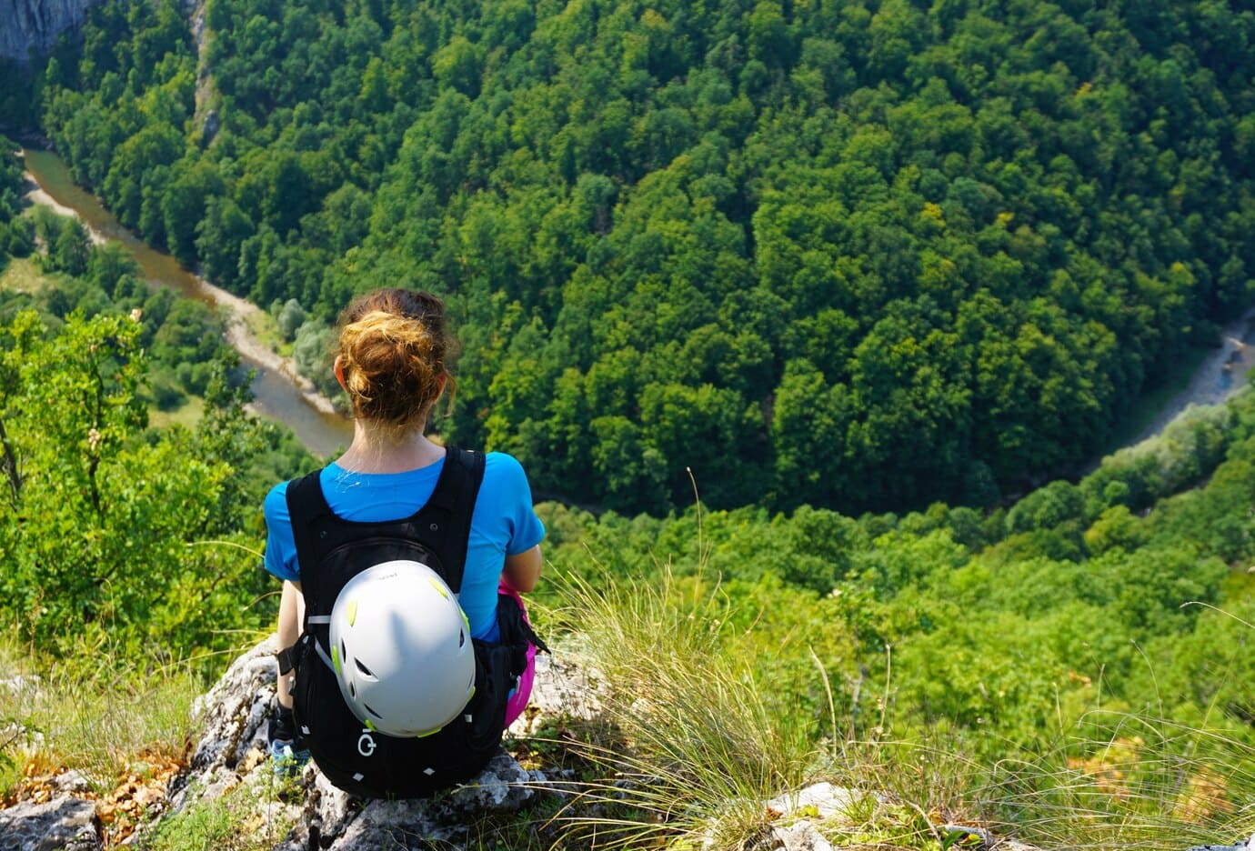 inquadratura dall'alto di una turista sportiva che pratica escursionismo su una montagna con casco ed attrezzatura